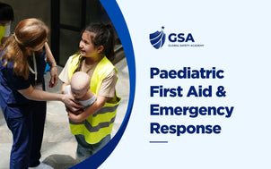 Global Safety Academy Paediatric First Aid & Emergency Response course banner showing an instructor guiding a participant wearing a yellow high-vis vest in handling an infant CPR training mannequin